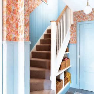 Hallway with carpeted staircase, blue wall panelling and floral wallpaper