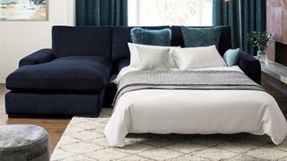 A navy blue chaise sofa bed with bedding