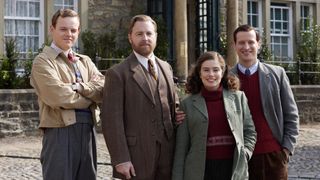 Callum Woodhouse as vet Tristan in All Creatures in a beige jacket and colourful jumper, Samuel West as head vet Siegfried in a dark tweed suit, Rachel Shenton as Helen in a green jacket and red jumper and Nicholas Ralph as James in a grey jacket and red jumper stand outside the veterinary practice in All Creatures Great and Small.