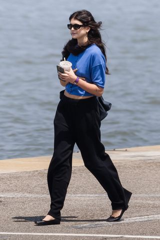 Kaia Gerber wearing a blue shirt and black pants