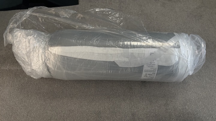 The Helix Premium Memory Foam Mattress Topper with GlacioTex compressed and rolled in plastic.