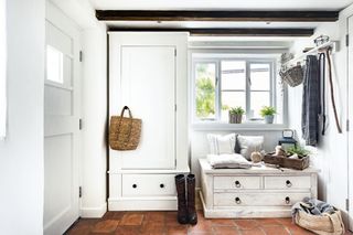 boot room with white cabinetry and bench seat with drawers under and red quarry tiled floor