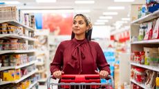 Woman pushing shopping cart down aisle of grocery store