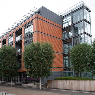 orange multistoried building with grey windows and green trees