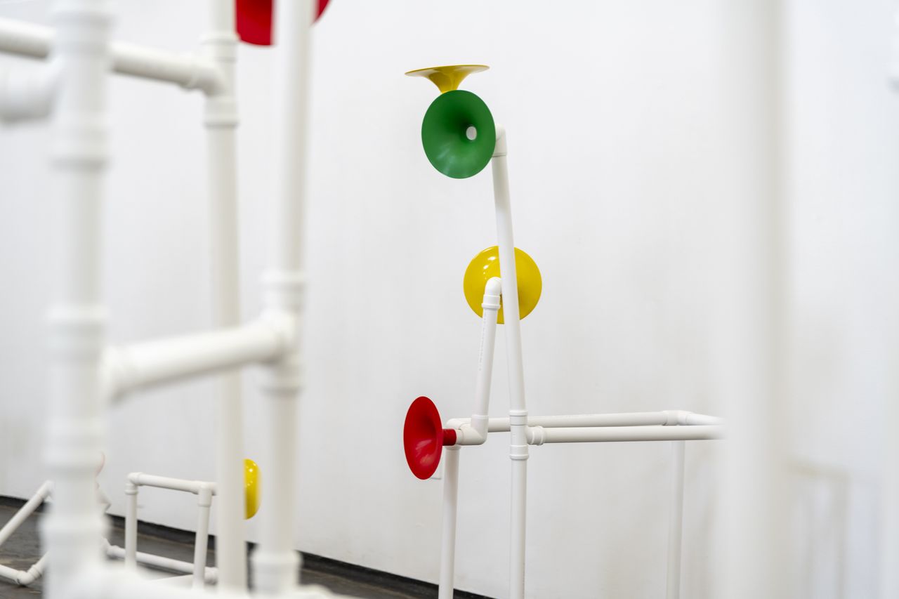 Installation in a former church made out of white pipes and colourful funnels