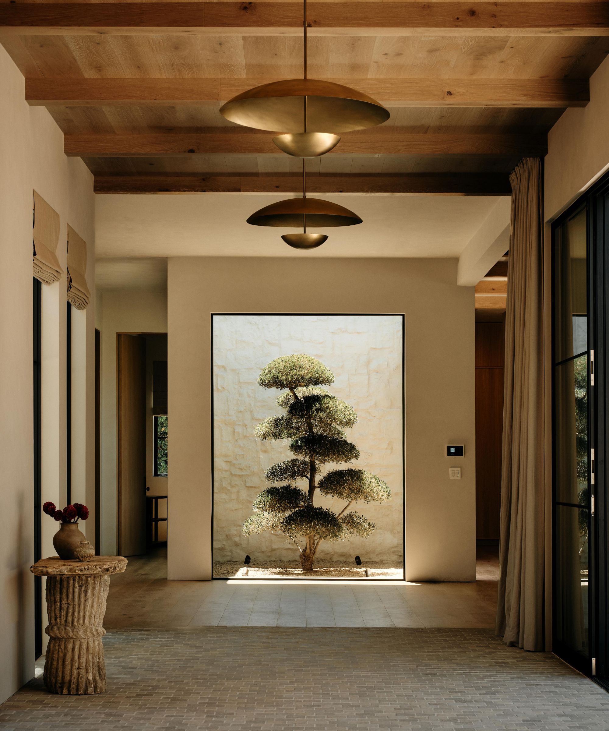 a European inspired entry in California with olive trees, oak ceiling and limestone floors