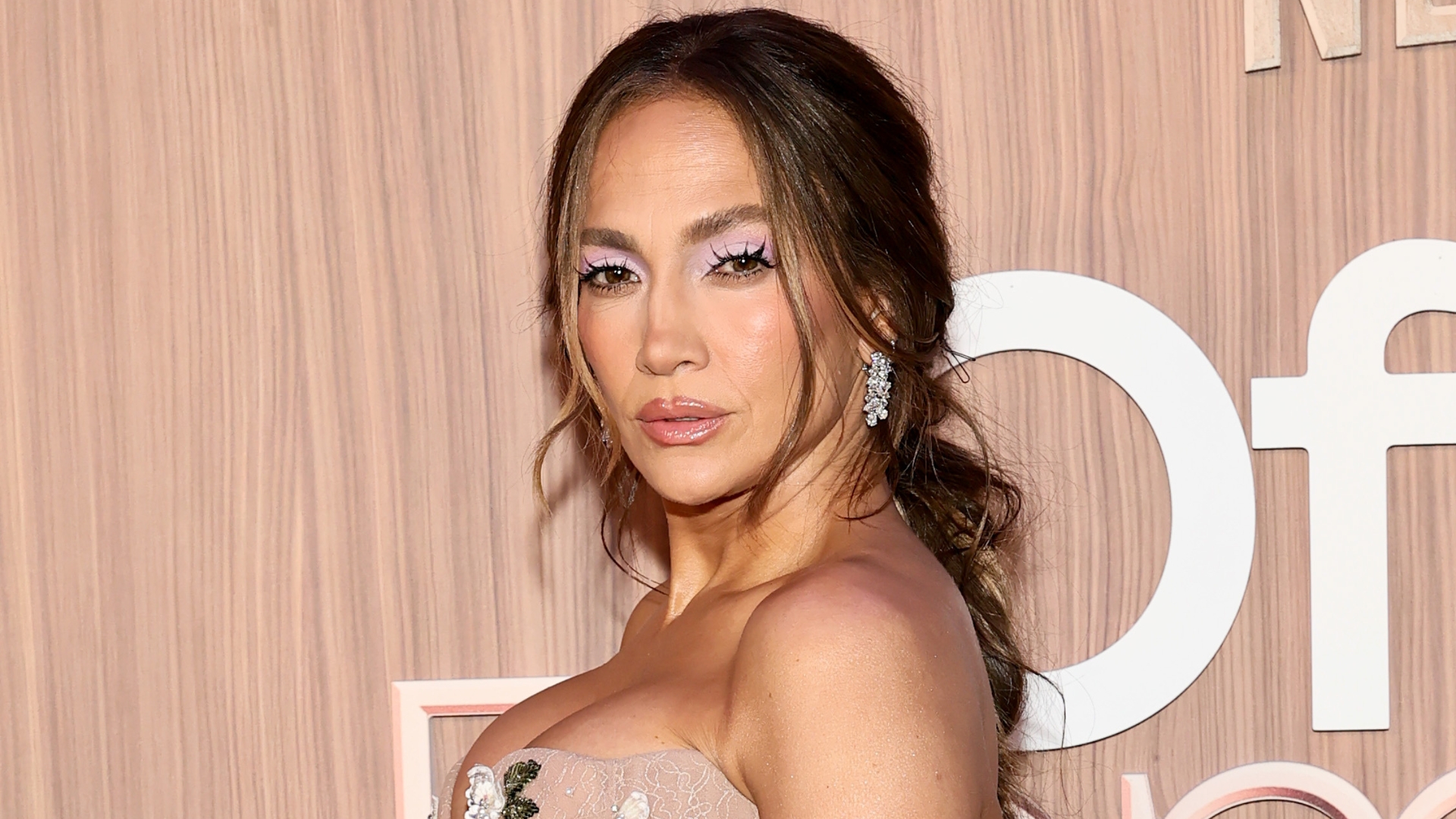 Jennifer Lopez is pictured with her hair in a low ponytail and wearing a nude, floral-embellished dress at Netflix's "Office Romance" New York Premiere at Regal Union Square on June 02, 2026, in New York City.