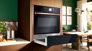 NEFF N29HA11Y1B built-in warming drawer in contemporary kitchen with wooden cabinets and green walls