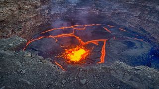 a lava lake in iceland with molten rock at the center of a rocky depression