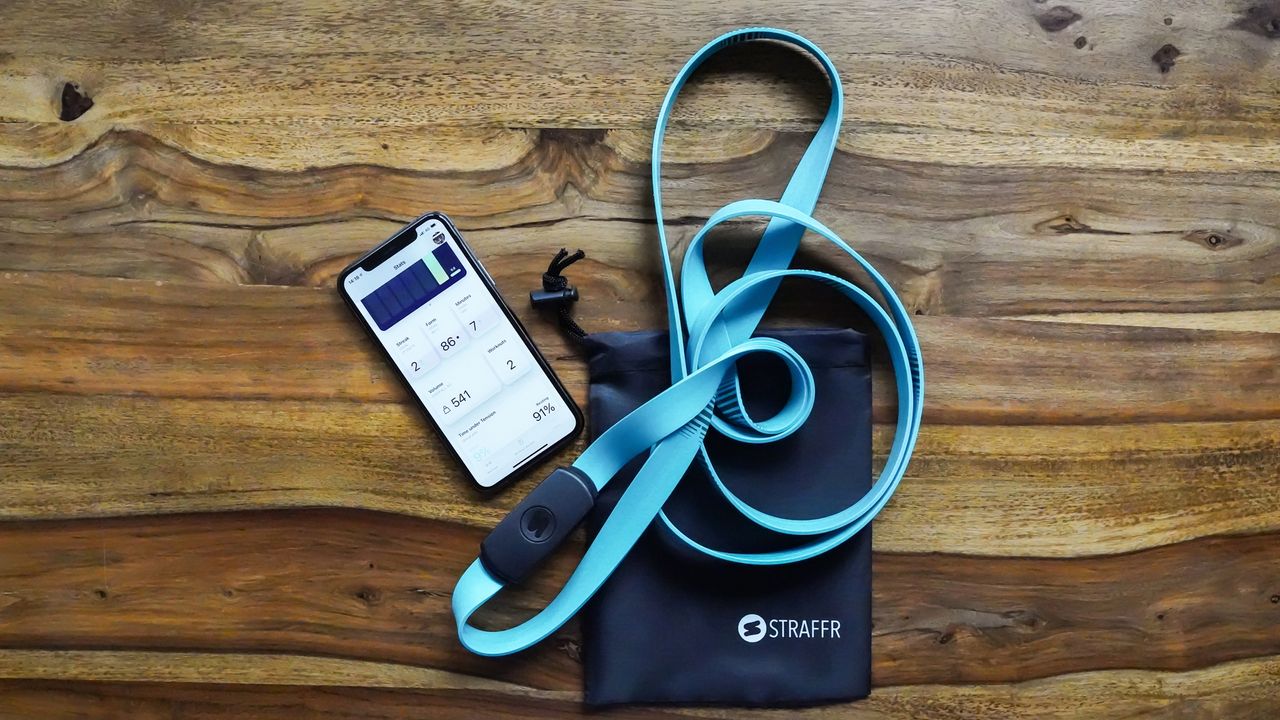 Straffr smart band lies next to a phone connected to the companion app