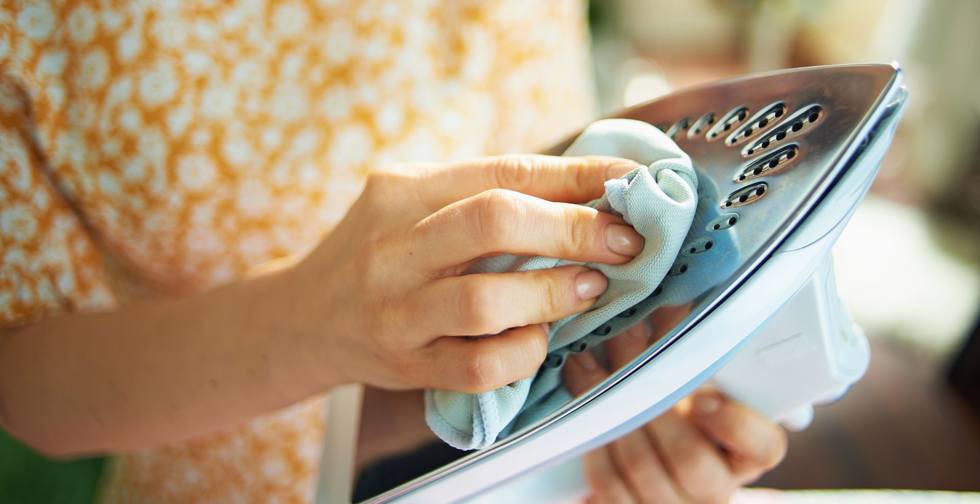 persone cleaning an iron with a microfibre cloth wiping the base plate