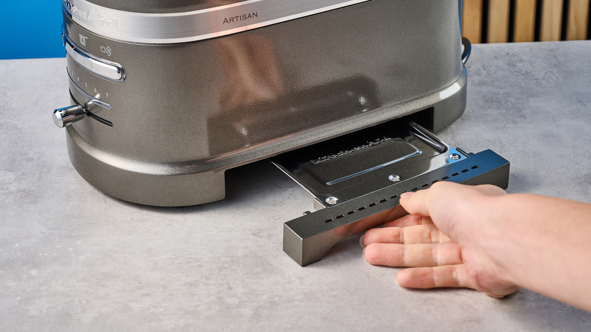 A photograph of the KitchenAid Pro Line toaster on a stone work surface with a blue and wooden background