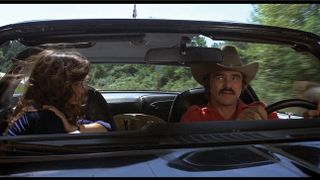 A scene from Smokey and the Bandit of Burt Reynolds driving a car next to Sally Field