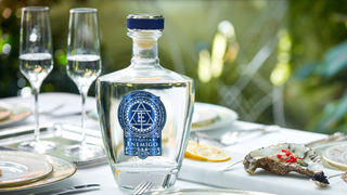 A bottle of Tequila Enemigo on a table next to champagne flutes