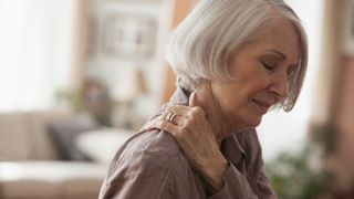 woman with joint pain nursing her shoulder