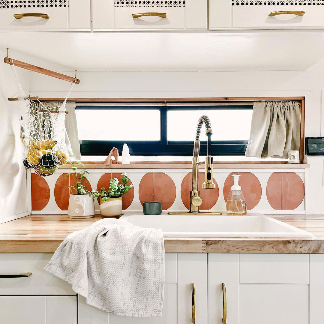 Kitchen sink with tile backsplash, bronze/gold faucets and cream cupboards