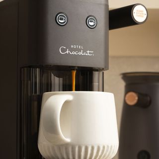 Image of Hotel Chocolat Podster pouring coffee into white mug