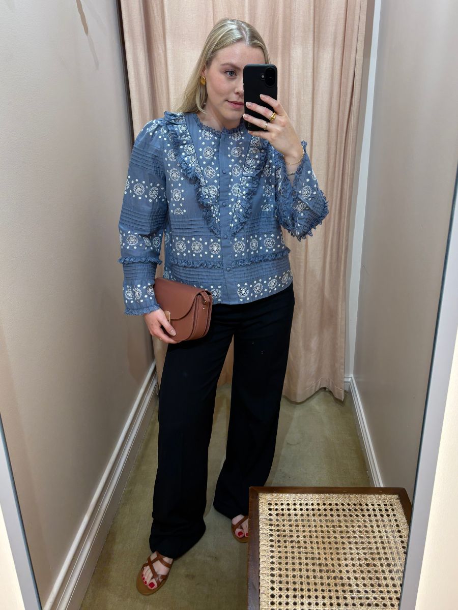 Woman wears blue blouse, black trousers and sandals
