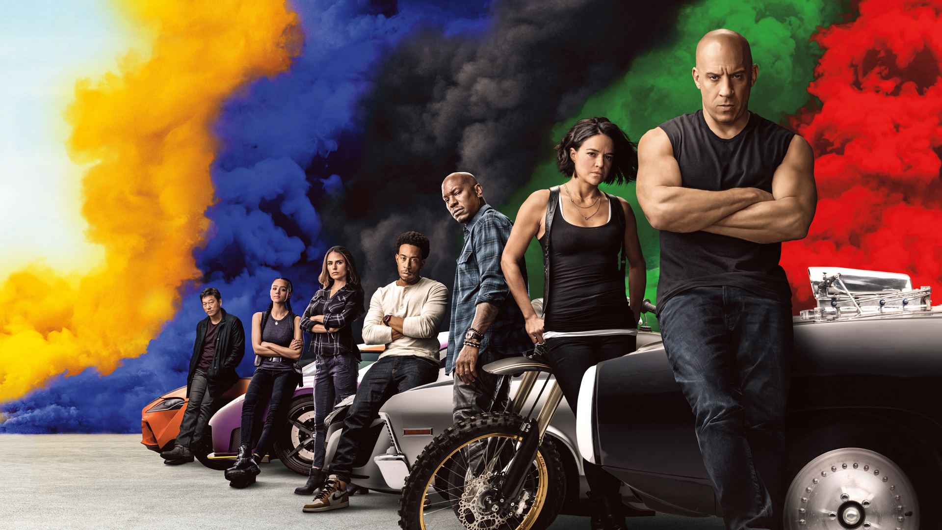 A promotional image for Fast 9, which shows the main cast leaning on some cars