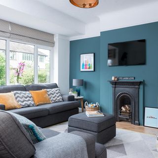 living room with blue wall grey sofa with cushion fire place and white window