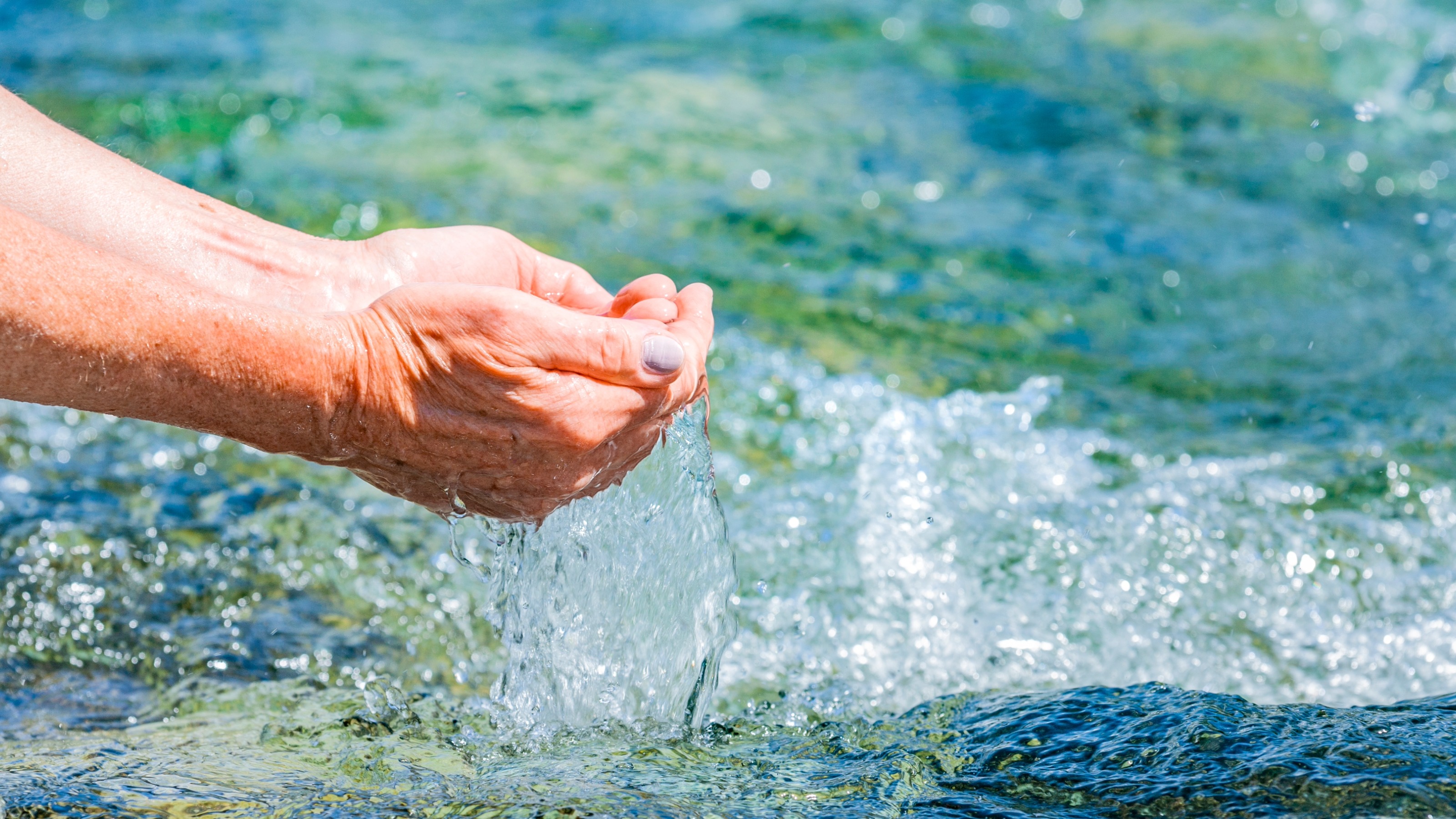 A woman's hands cupping clear water from the sea