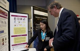 The winner of the 2011 Siemens Competition in Math, Science & Technology $100,000 individual grand prize, Angela Zhang, shows her work to Eric Spiegel, CEO of Siemens Corporation.