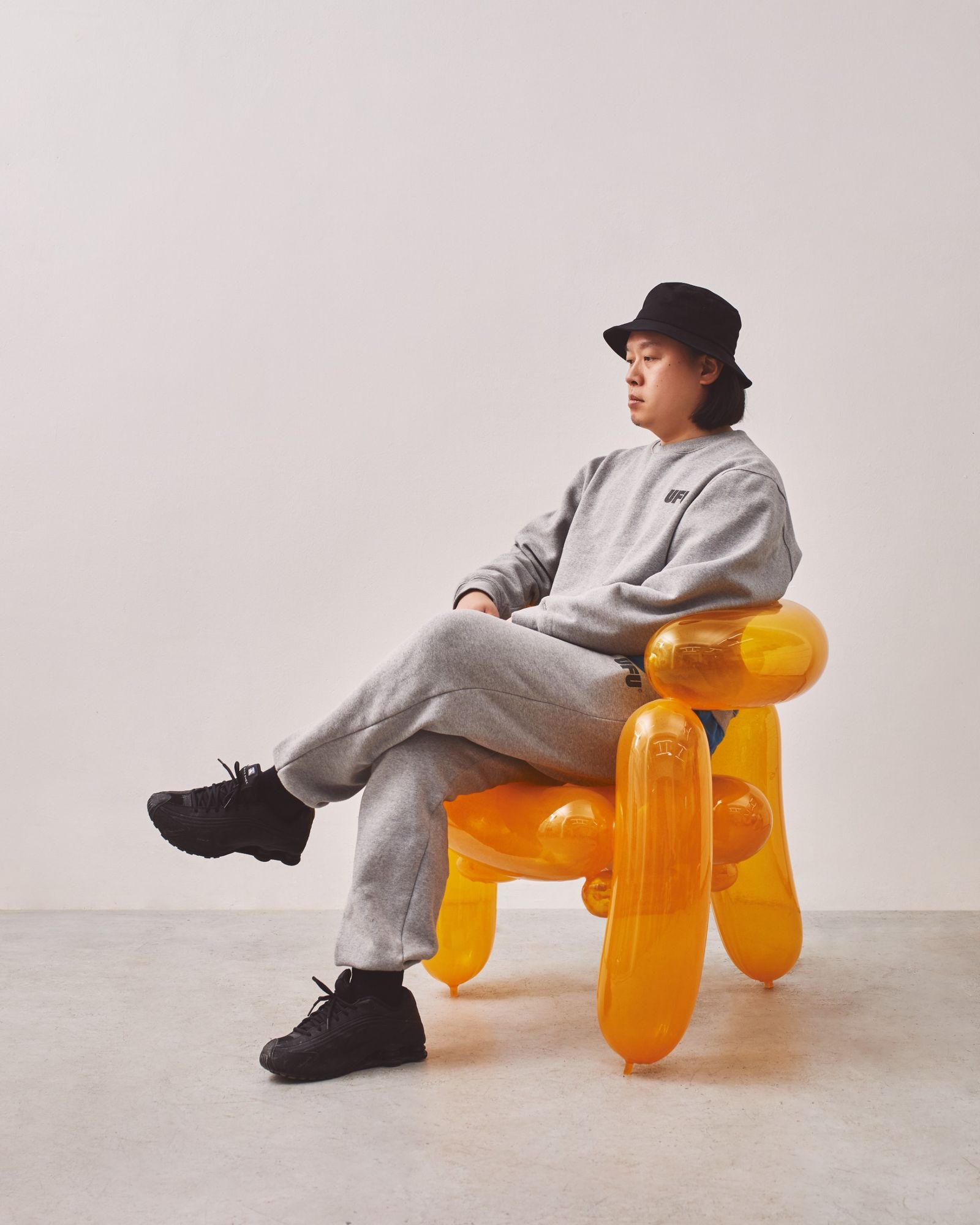 Designer sits on resin chair that looks like it's made from balloons