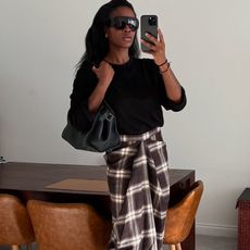 Woman in black sweater and plaid skirt