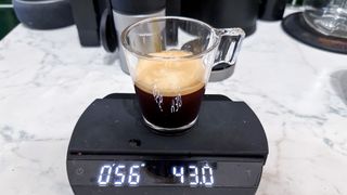 An espresso shot poured into an espresso glass on top of a coffee scale.