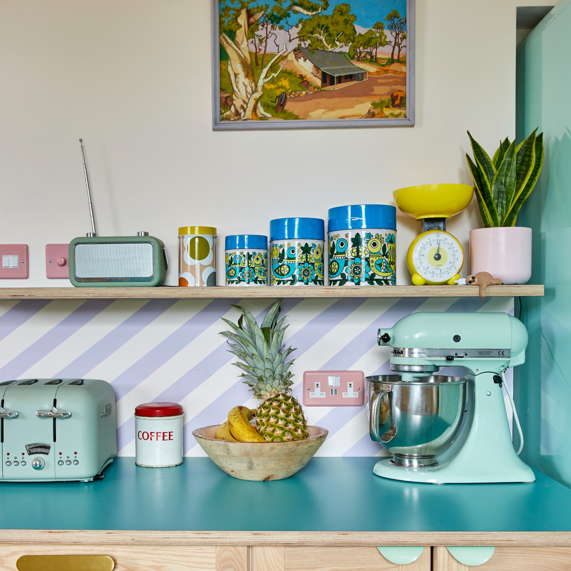 A kitchen with open shelving and worktops in aqua blue with tonal kitchen appliances