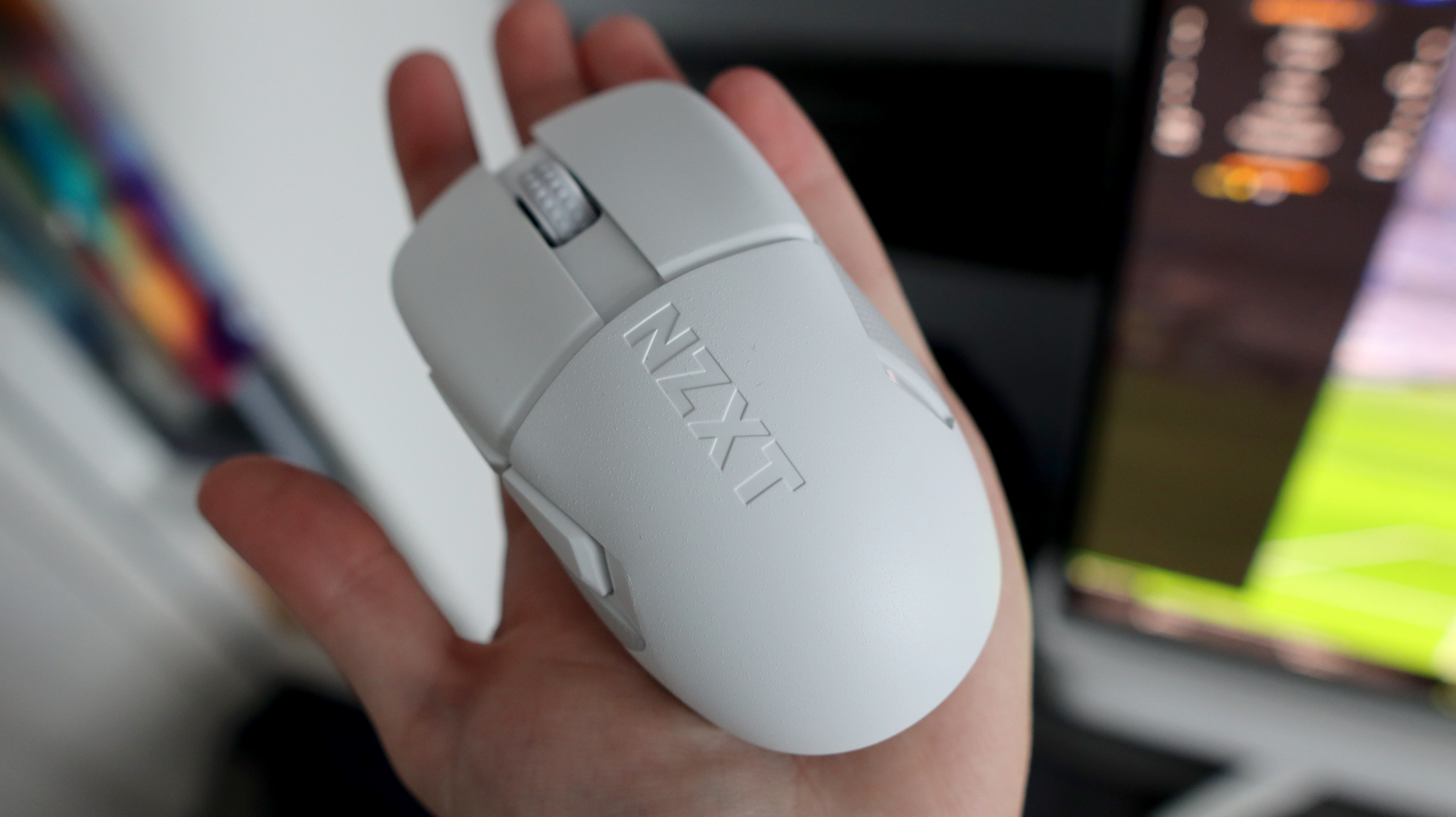 An NZXT Lift Elite Wireless gaming mouse in white set-up on a desk.