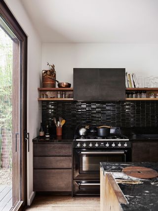 a dark wood kitchen with black backsplash