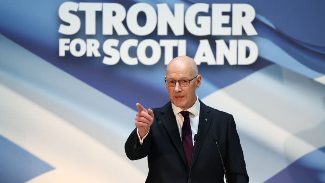 John Swinney, the new leader of the SNP, delivers a speech in front of a background that says &#039;stronger for Scotland&#039;