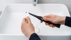 A man putting toothpaste on his electric toothbrush