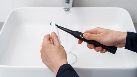 A man putting toothpaste on his electric toothbrush