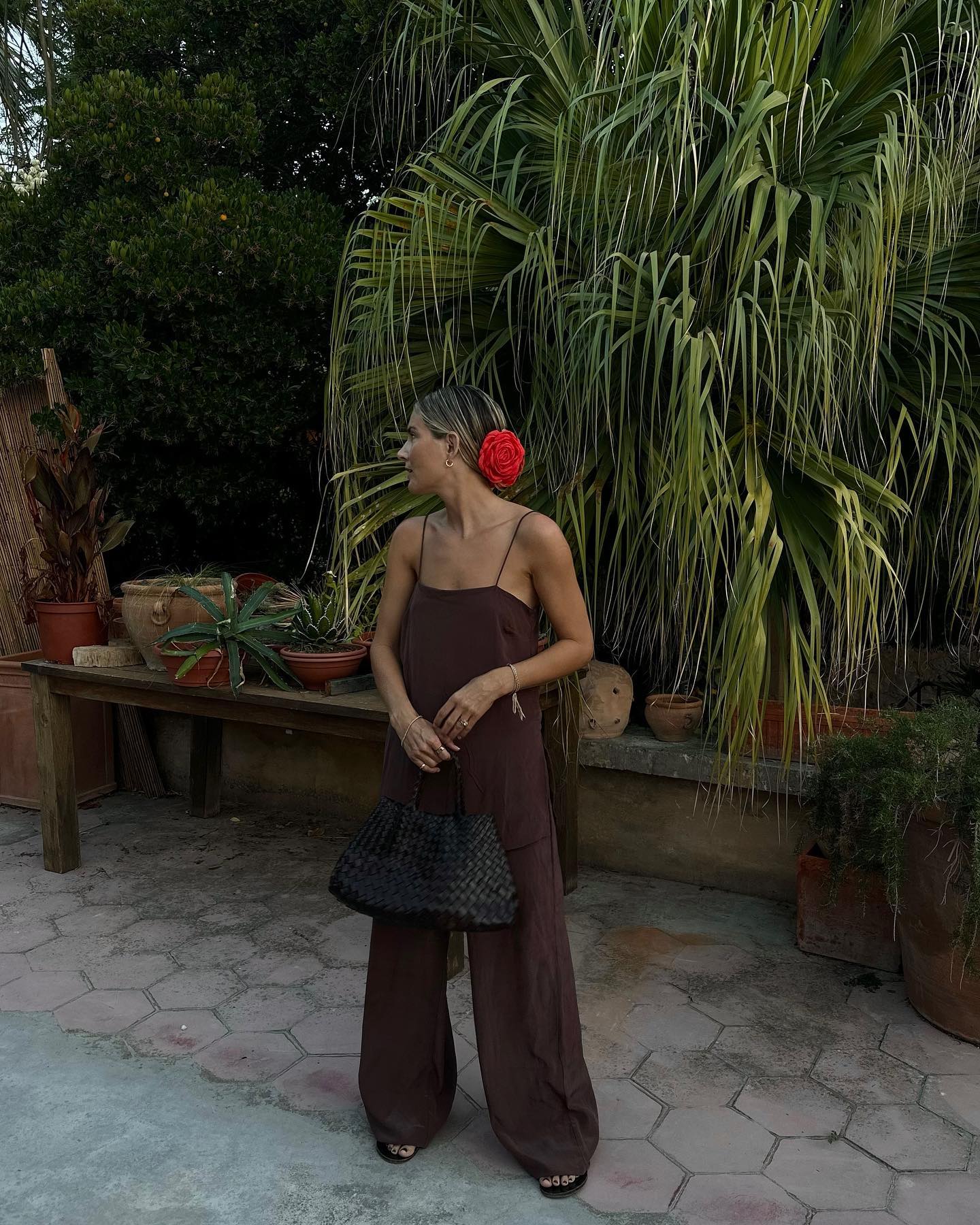 Elegant Summer Style: @lucywilliams02 wears a brown linen jumpsuit with a red floral corsage in her hair