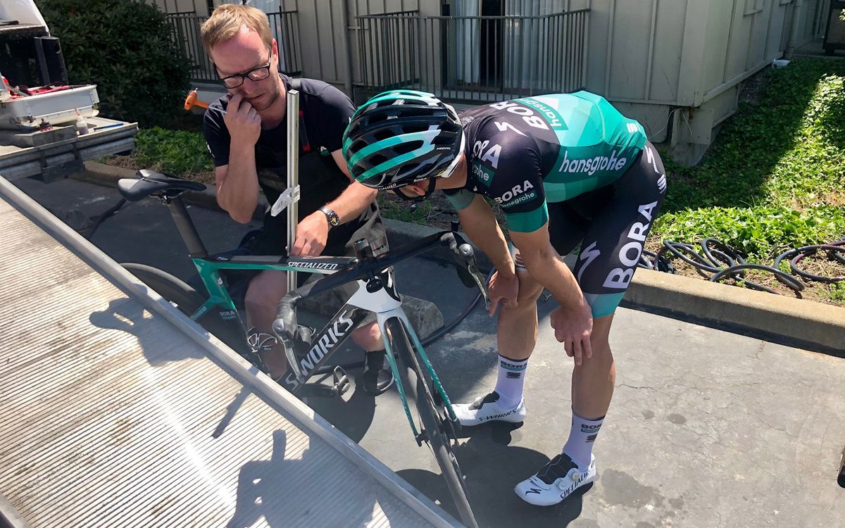 A Bora-hansgrohe rider works with his mechanic to get his position dialled ahead of the race