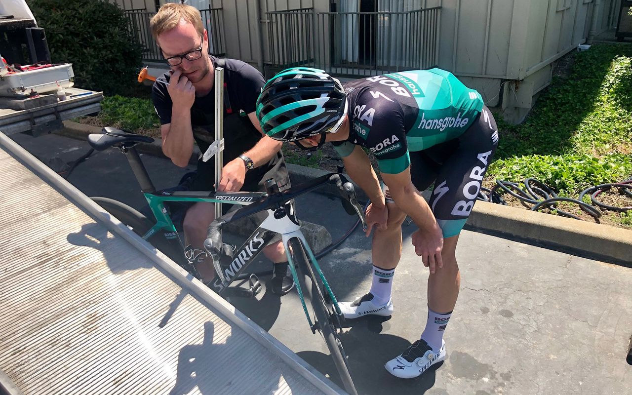 A Bora-hansgrohe rider works with his mechanic to get his position dialled ahead of the race