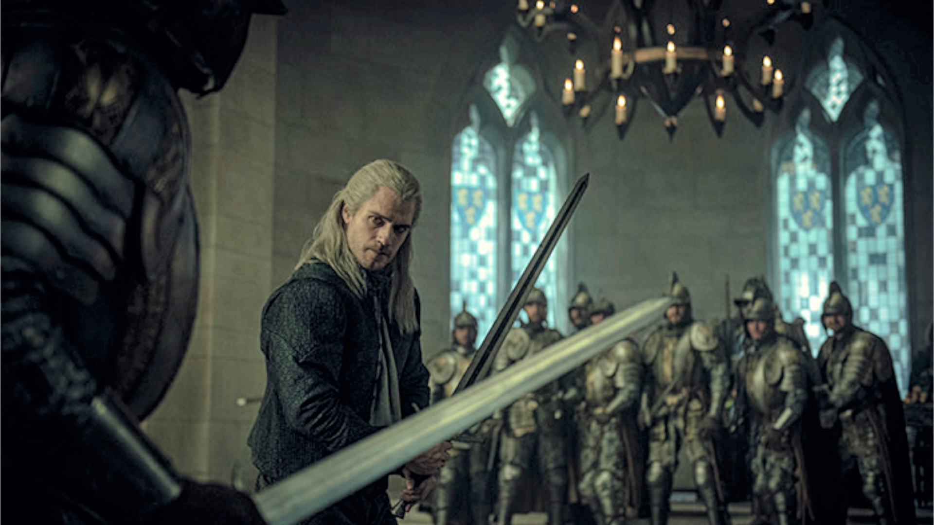 Geralt holding a sword ready to fight in the hall of a castle