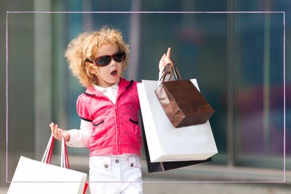 Baby girl carrying designer shopping bags