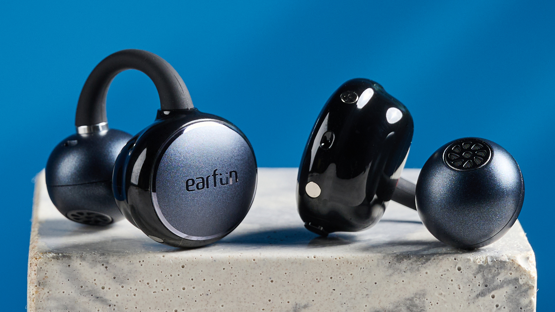 EarFun Clip open-earbuds photographed in front of a blue background.