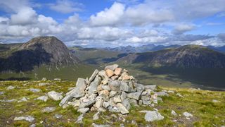 A rock cairn on a mountain with hills in the background