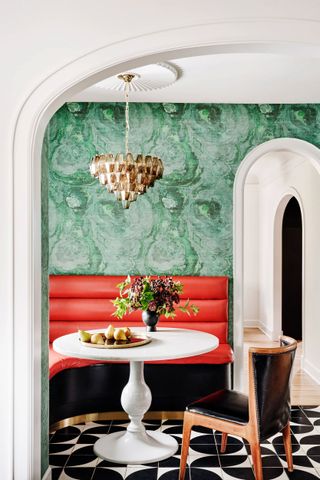 a dining room with red banquette seating and green walls