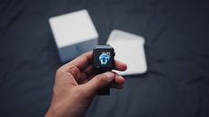 Man holding Apple Watch above open box on navy blue background