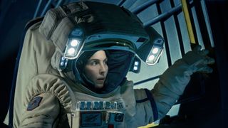 Apple TV Plus' sci-fi thriller Constellation stars Noomi Rapace as an astronaut, pictured here in a grey space suit and 'fishbowl' helmet with double LED lights on each side.