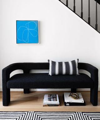 black bench with blue artwork and stairs behind with geometric rug
