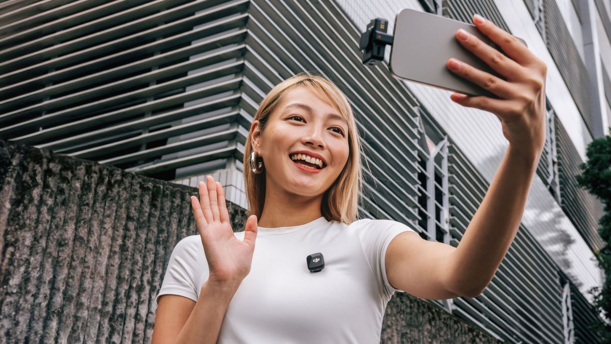 Person waving using DJI Mic mini with RX in phone and TX on white top