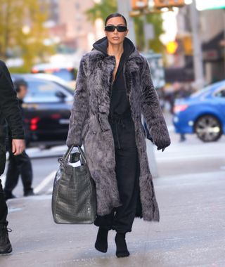 kim kardashian wears a giant fur coat with black sweats and a maxi birkin bag in nyc