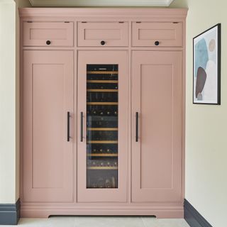 pink kitchen cupboards with wine column fridge in middle