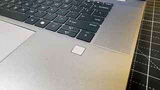 HP ZBook Studio 16 G11 mobile workstation on a white desk with a black table mat, against a yellow backdrop.